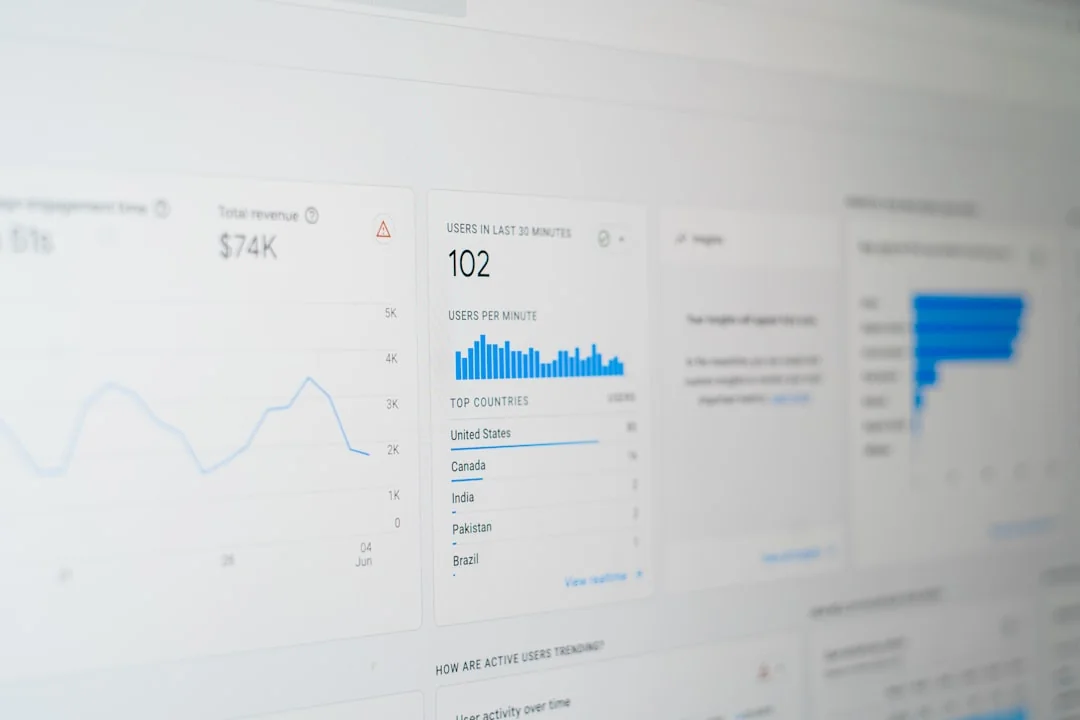 A contemporary workspace where hands review marketing data on a laptop alongside paper documents.